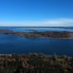Pogled iz vazduha na veliko bavarsko jezero sa ostrvima i planinama u daljini